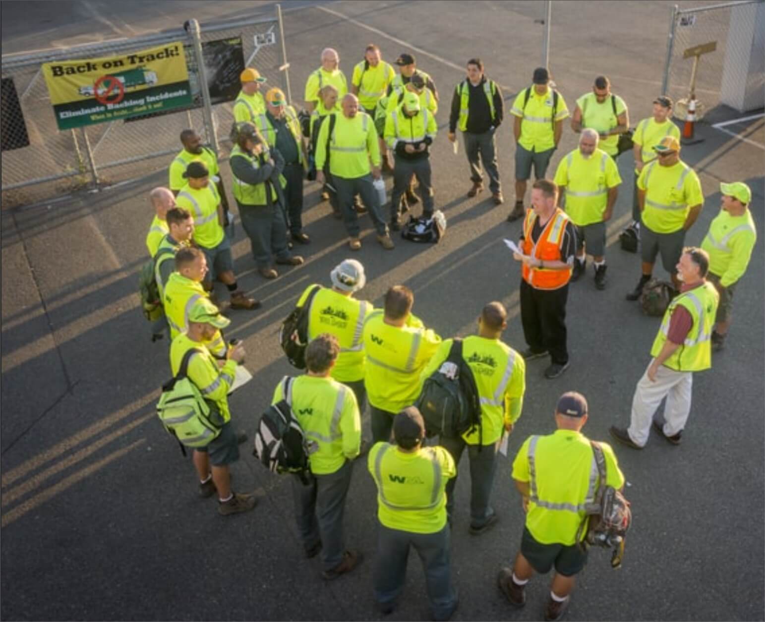 Group of WM frontline workers stand in a circle for their morning meeting